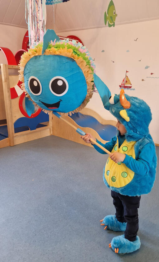Boy breaking a piñata at the carnival party in Mariposa Nursery