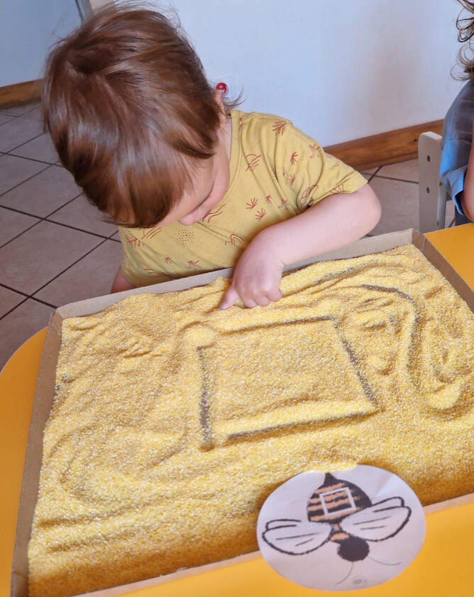 Untitled Child finger-painting on groats at Mariposa Nursery